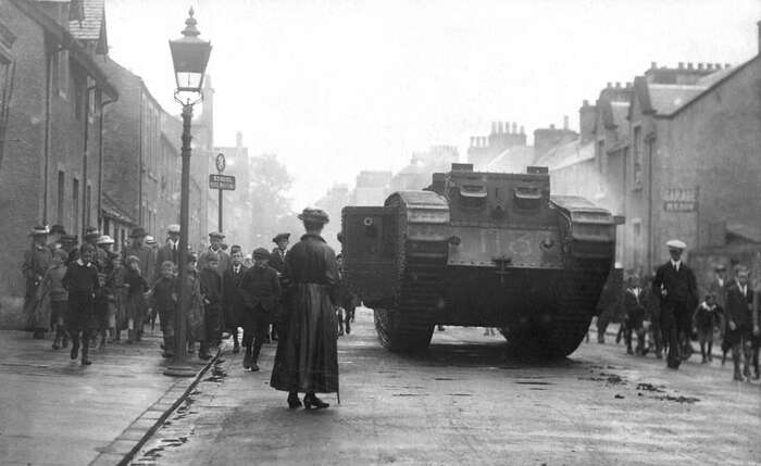 World War 1 Mk V (Male) Tank in Callander high street with crowds and woman in foreground