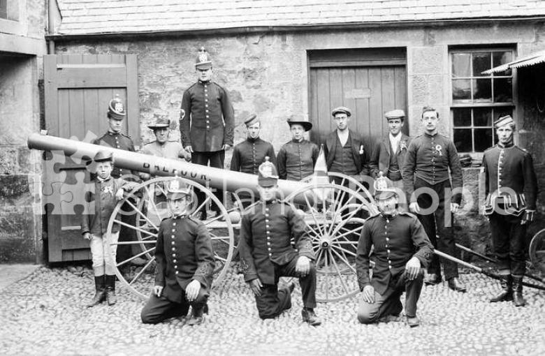 Volunteer firemen and estate workers with a pump mounted on wheels, c 1905