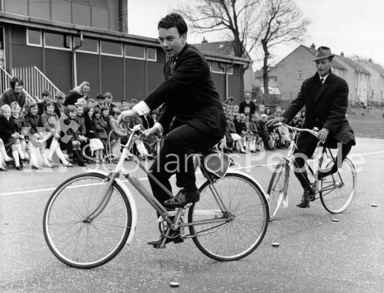 Actors Peter Byrne and Geoffrey Adams riding bicycles, 1967