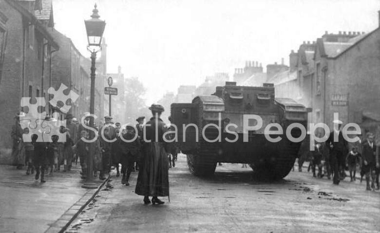 World War 1 Mk V (Male) Tank in Callander high street with crowds and woman in foreground