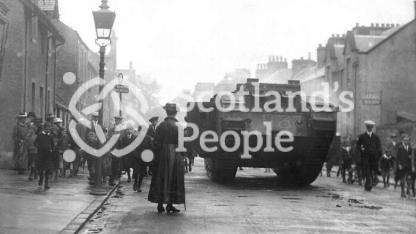 World War 1 Mk V (Male) Tank in Callander high street with crowds and woman in foreground World War 1 Mk V (Male) Tank in Callander high street with crowds and woman in foreground