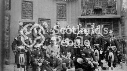 Officers and men of [The Black Watch, (Royal Highlanders)] standing in front of Egyptian vernacular building.