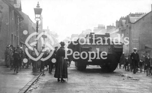 World War 1 Mk V (Male) Tank in Callander high street with crowds and woman in foreground World War 1 Mk V (Male) Tank in Callander high street with crowds and woman in foreground