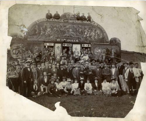 Photograph of circus performers in front of a ticket booth for ‘Lord’ George Sanger’s Circus. The entrance façade has the wording ‘Lord George the Imperial Sanger/The Leading Show of the World/ 3 Times Patrionized by the Queen’ painted on the front. Reproduced with permission of the University of Sheffield.