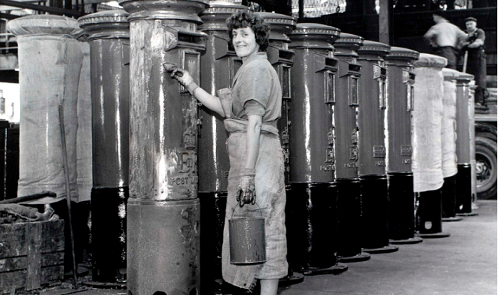 Black and white photo of a person painting a post box
