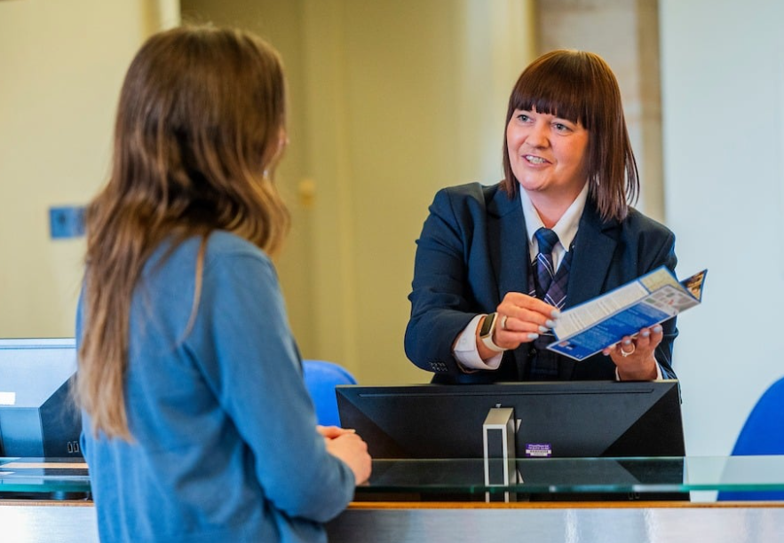 A visitor talking to a Scotland's People front staff at a reception desk.