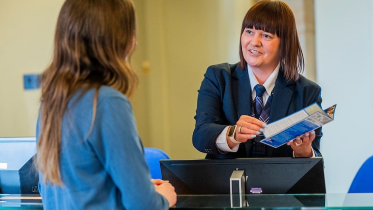 A visitor talking to a Scotland's People front staff at a reception desk.